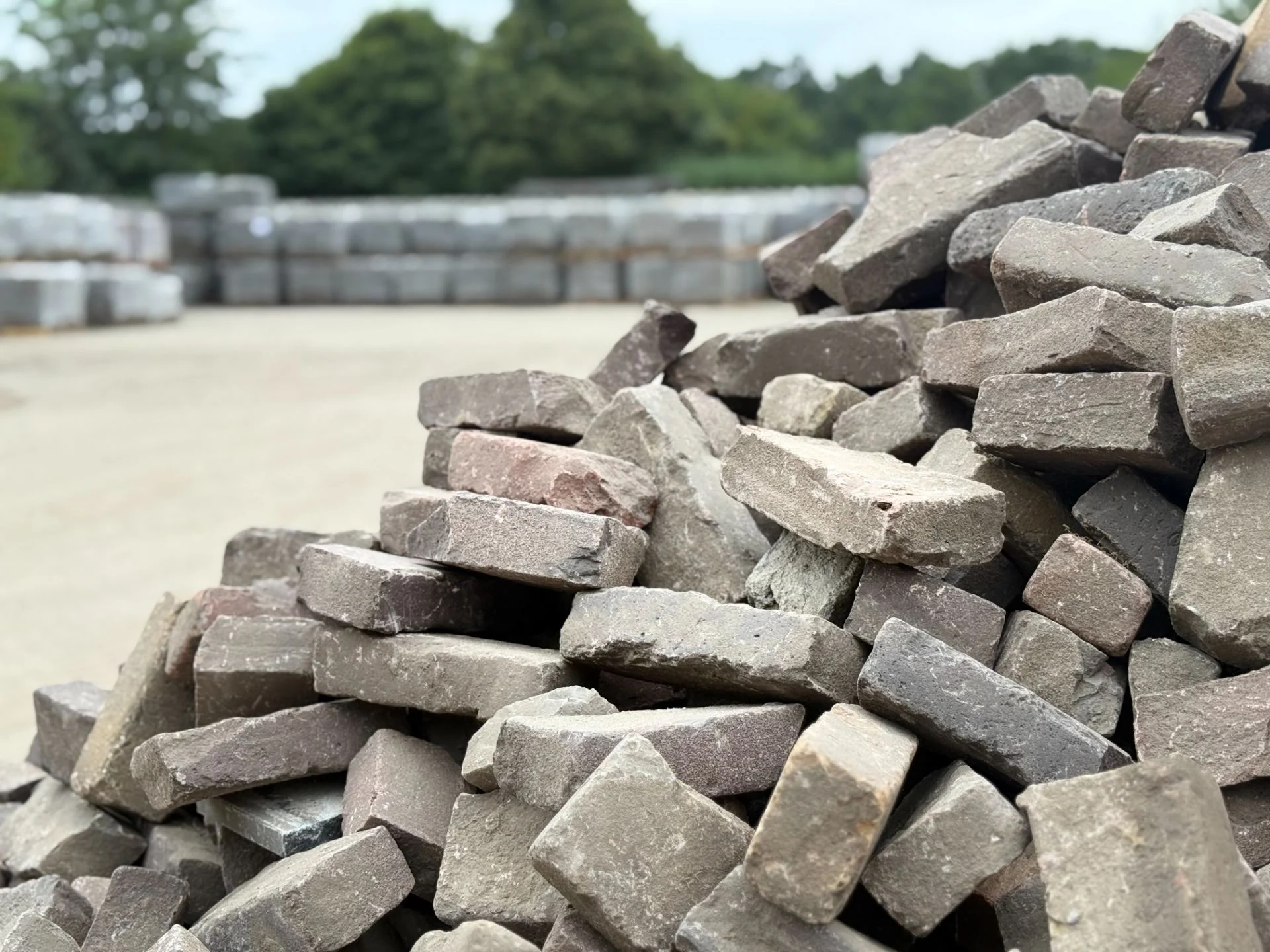 Gebruikte klinkers op het materiaalterrein van LujoGardens, met opgeslagen partijen op de achtergrond