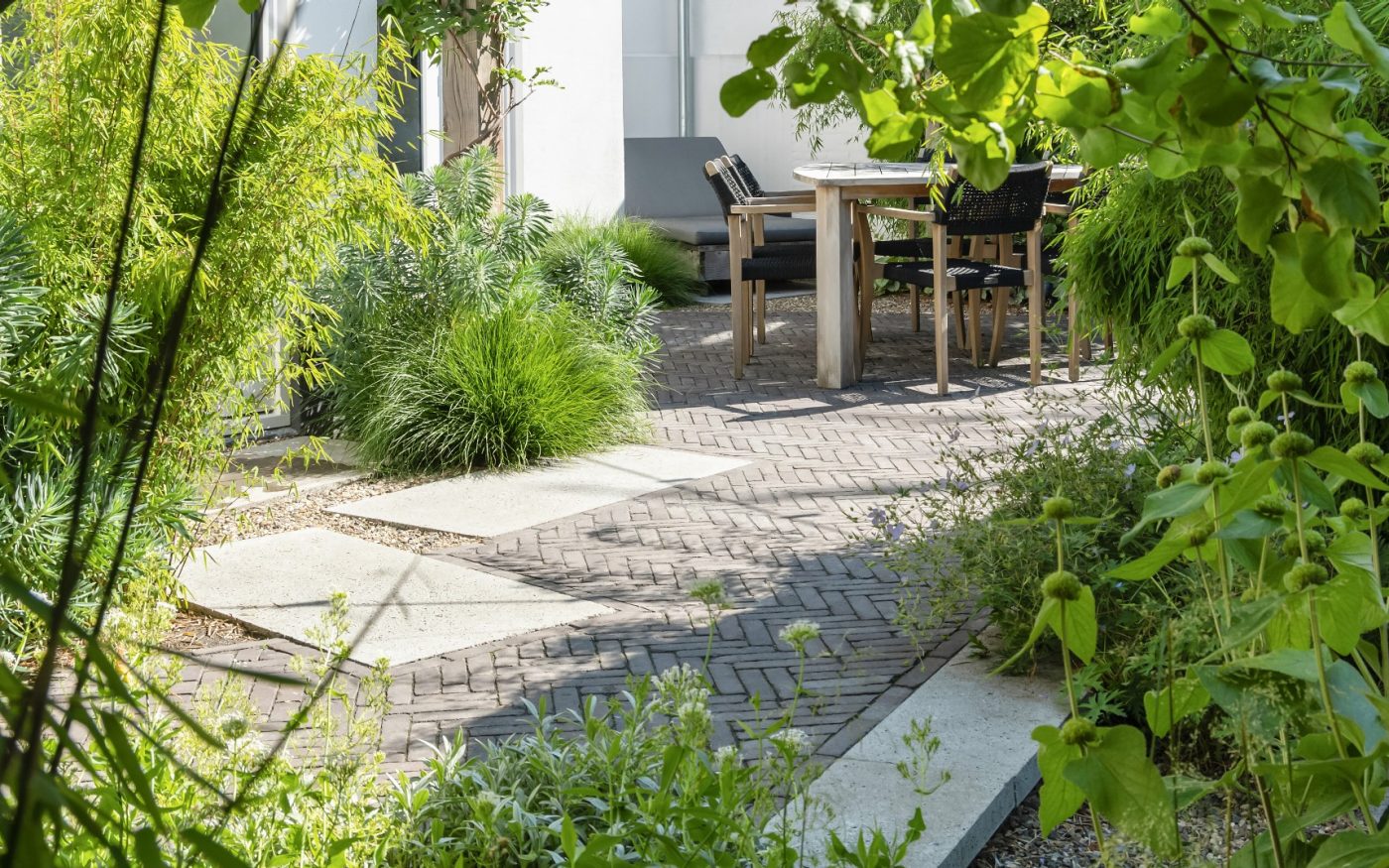 Gebakken klinkers in een groene tuin met een terras en staptegels