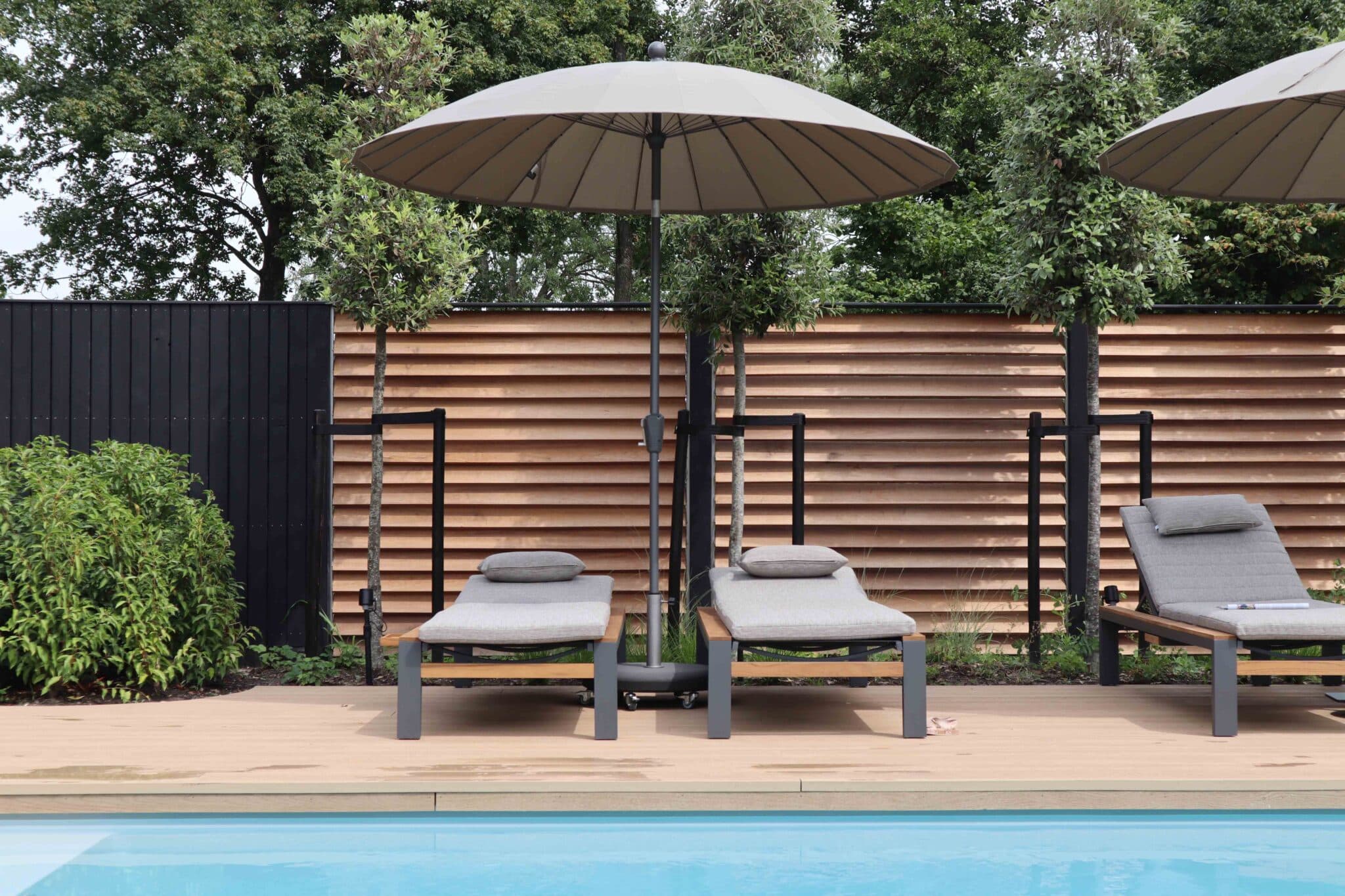 Ligstoelen en parasol aan het zwembad in de showtuin