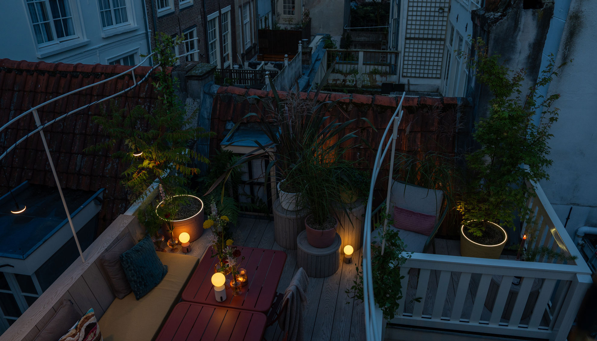 Verlicht dakterras tussen de Amsterdamse woningen in de avond