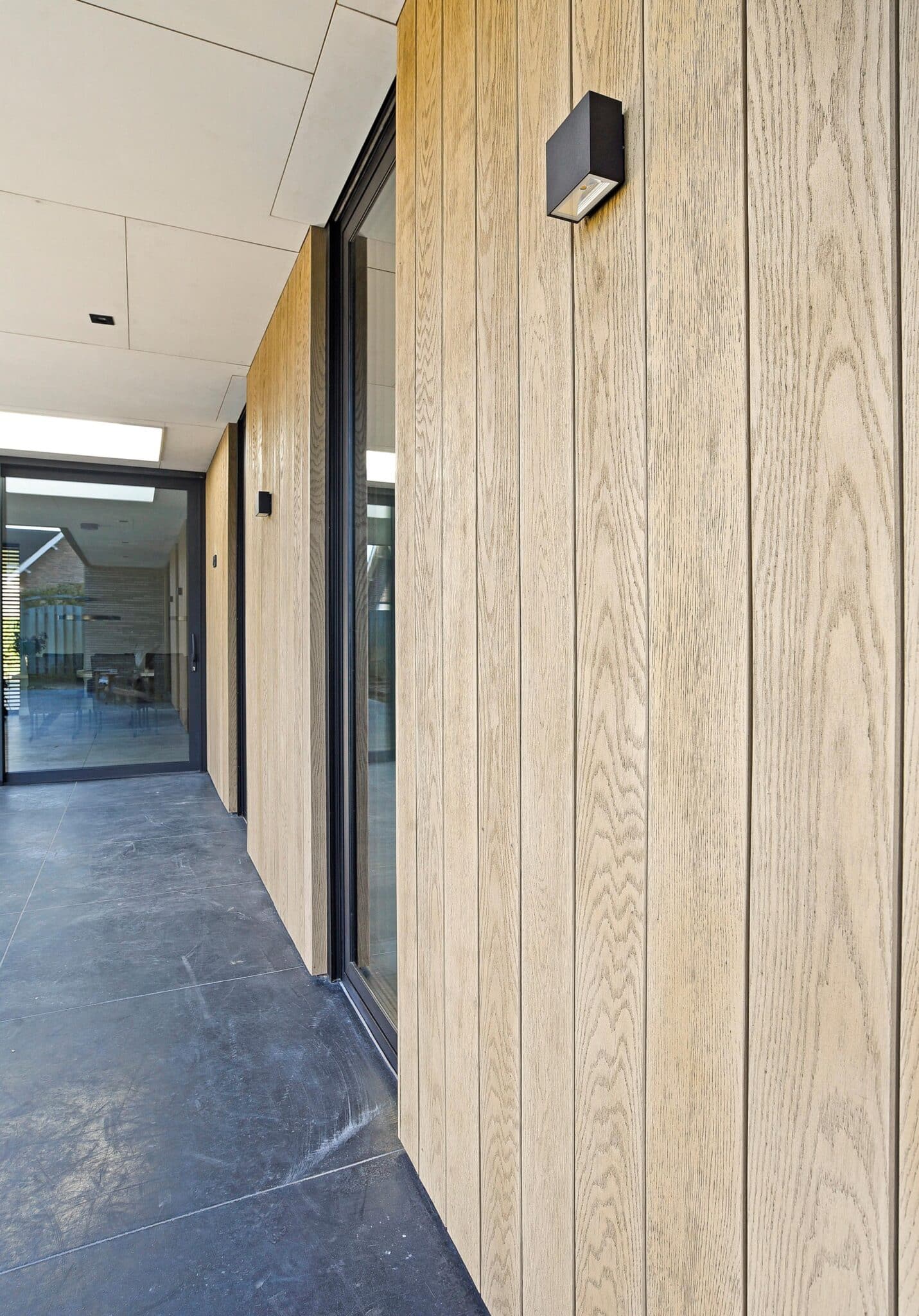 Detail van verticale gevelplanken naast een glazen deur