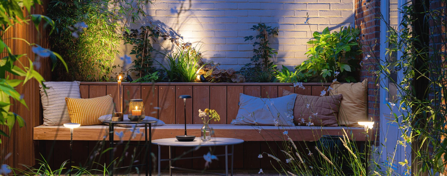 Zacht verlichte in-lite voorbeeldtuin bij een bakstenen muur