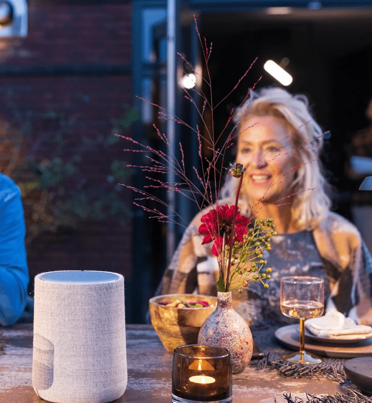 Diner in de tuin met in-lite verlichting en een slimme luidspreker op tafel