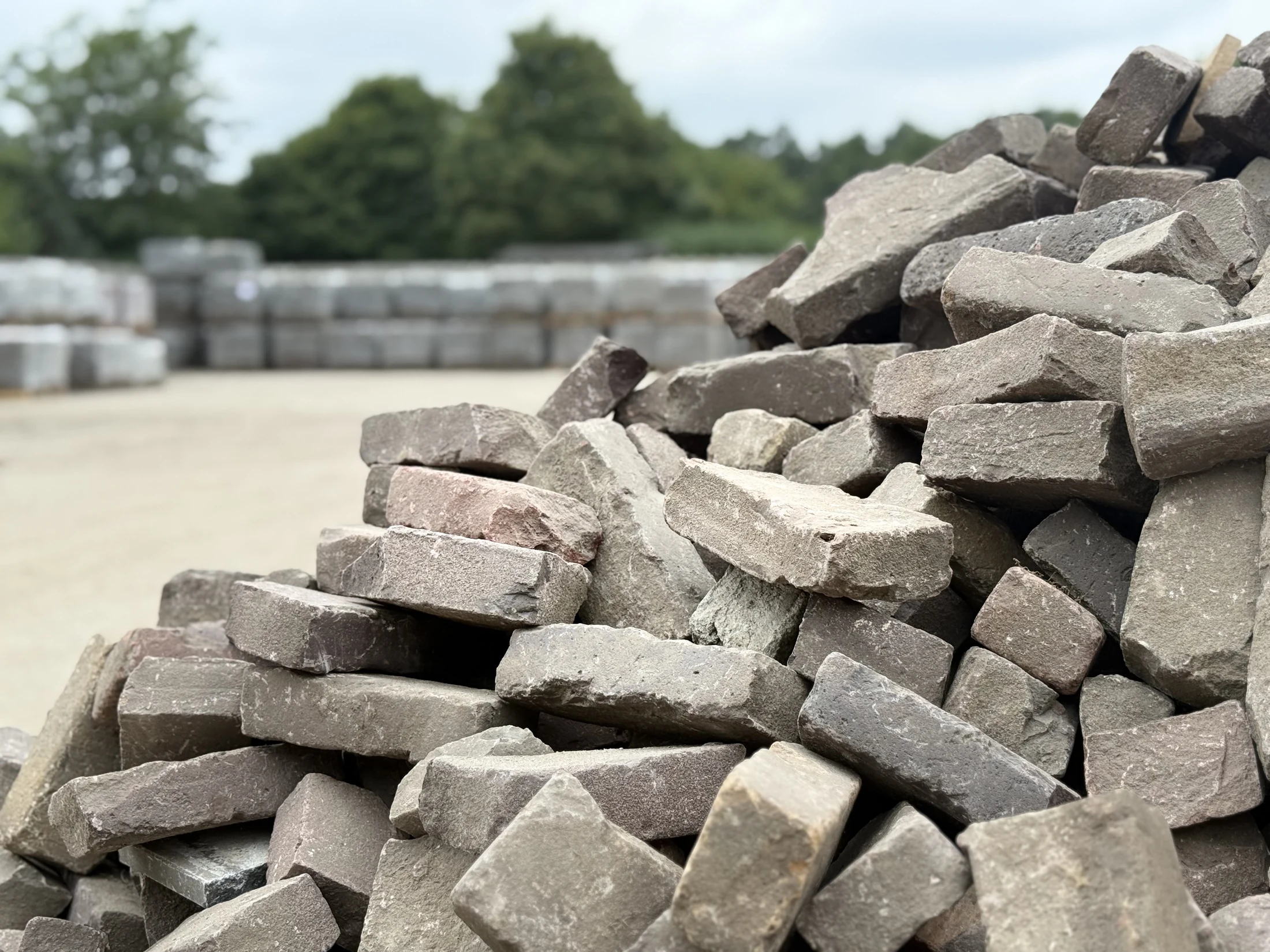 Gebruikte klinkers met op de achtergrond gestapelde pallets op het opslagterrein