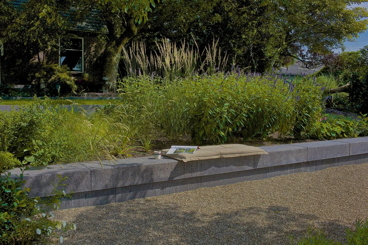 Schellevis zitelementen langs weelderige beplanting in een tuin in Geffen